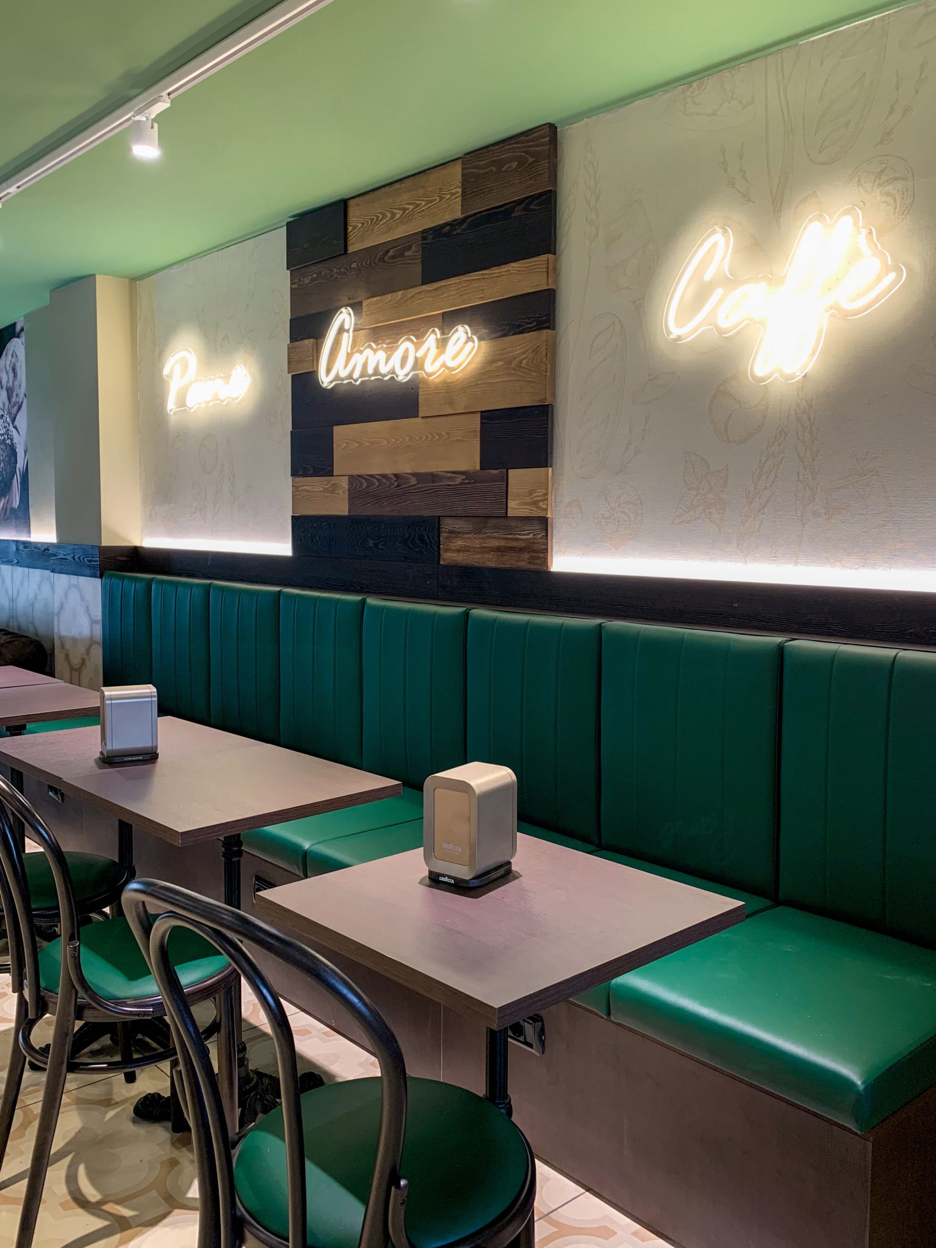 Nuova sede Panfé a Novara in Corso Italia, 5 - Interni della sede con sedute comode con divanetti color verde acqua, tavoli quadrati e sedie nere. Locale elegante con colori che richiamano l'identità visiva di Panfé